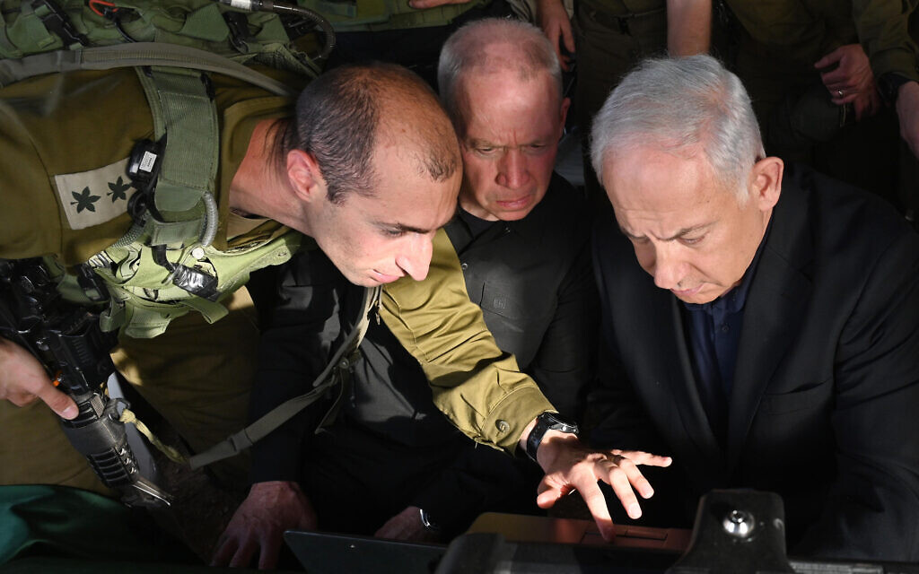 Defense Minister Yoav Gallant (center) and Prime Minister Benjamin Netanyahu (right) are briefed at the scene of a terror attack in the Jordan Valley in the West Bank on April 7, 2023. (Haim Zach / GPO)