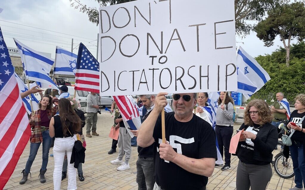 Protesters against the government's judicial overhaul greet participants of the Jewish Federations of North America’s General Assembly in Tel Aviv, April 23, 2023. (Carrie Keller-Lynn/Times of Israel)
