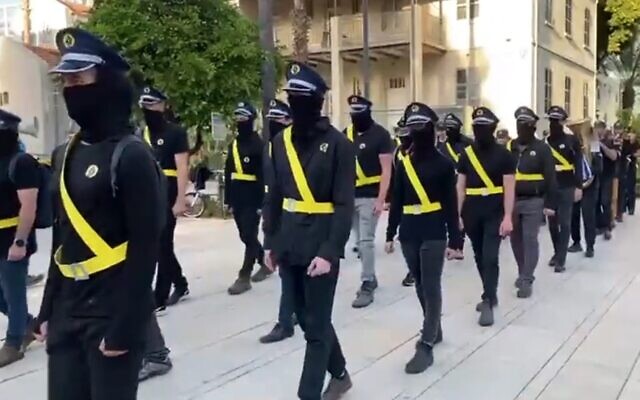 Demonstrators, dressed up as members of a national guard force that National Security Minister Itamar Ben Gvir wants to form, parade in Tel Aviv on April 1, 2023. Critics warn that the force could be used by the far-right minister as his private militia. (Twitter screenshot, used in accordance with clause 27a of the Copyright Law)