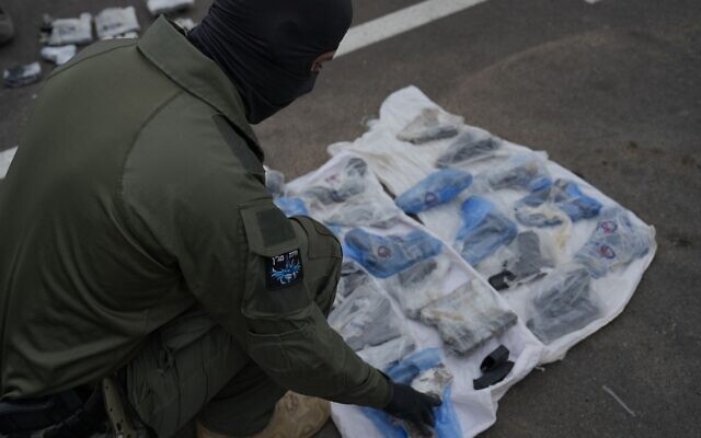A Magen unit police officer inspects weapons seized by Israeli security forces during a gun-smuggling attempt along the border with Jordan on April 20, 2023. (Israel Police)