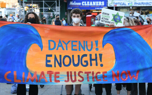 Dayenu CEO Jennie Rosenn holds up a banner after addressing the crowd at a rally urging New York State lawmakers to pass the Climate and Community Investment Act in New York, April 7, 2021. (Gili Getz / Courtesy of Dayenu via JTA)