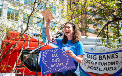 Rabbi Laura Bellows, now Dayenu's director of spiritual activism and education, waves matzah as she encourages major financial organizations to divest from fossil fuels at a rally in Washington, DC, April 20, 2022. (Bora Chung | Survival Media Agency / Courtesy of Dayenu via JTA)