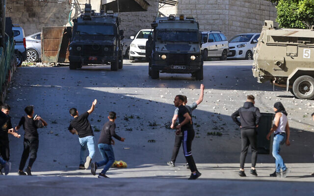 Palestinians throw stones at Israeli forces as they clash during an Israeli army raid in the West Bank city of Nablus on May 4, 2023. (Zain Jaafar / AFP)