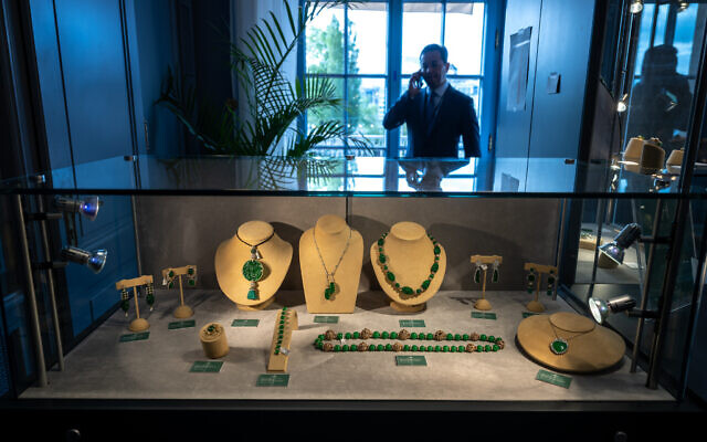 This photograph taken on May 8, 2023, shows Christie's international head of jewelry Rahul Kadakia speaking on his mobile telephone behind a display case of jewels during a press preview of the 'World of Heidi Horten' sales in Geneva (Fabrice COFFRINI / AFP)