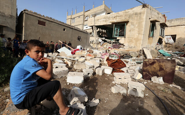 A boy sits amidst the rubble near of the house of Ahmed Abu-Deka on May 11, 2023, the deputy of the commander of a rocket launch unit killed by Israel on May 10. (Photo by SAID KHATIB / AFP)