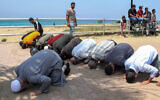 Muslim men pray along an a pavement by a public beach after a demonstration against modesty customs, in Lebanon's southern city of Sidon on May 21, 2023. (MAHMOUD ZAYYAT/AFP)