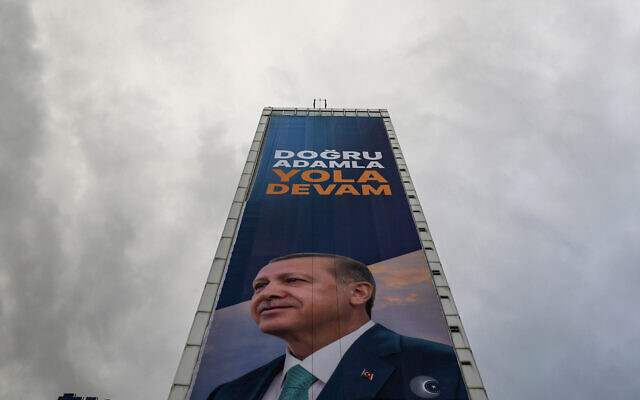 A huge electoral poster bearing a portrait of Turkey's President Recep Tayyip Erdogan with a slogan which reads "Keep going with the right man" covers the facade of a high-rise building in Ankara, on May 23, 2023, (Adem Altan/AFP)