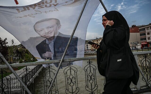 A woman walks past a flag of Turkish President Recep Tayyip Erdogan on a bridge above Coruh river at Bayburt city center, north-east Turkey, on May 23, 2023. (Ozan Kose/AFP)