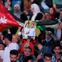 A man holds up a pre-wedding poster showing Jordan's Crown Prince Hussein and his fiance Rajwa al-Saif, during a free concert to celebrate the upcoming wedding at Amman International Stadium on May 29, 2023. (Khalil MAZRAAWI / AFP)