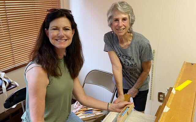 Jennifer Bullock and Cory Schneider weave on the newly-renovated loom that was donated by Deborah Lamensdorf Berman. (Congregation Neve Shalom via JTA)