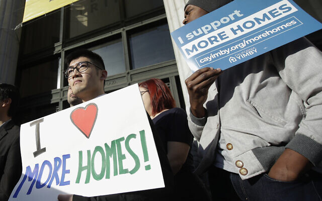 Men hold up signs at a rally outside of City Hall in Oakland, California, in support of more housing on January 7, 2020. (AP Photo/Jeff Chiu, File)