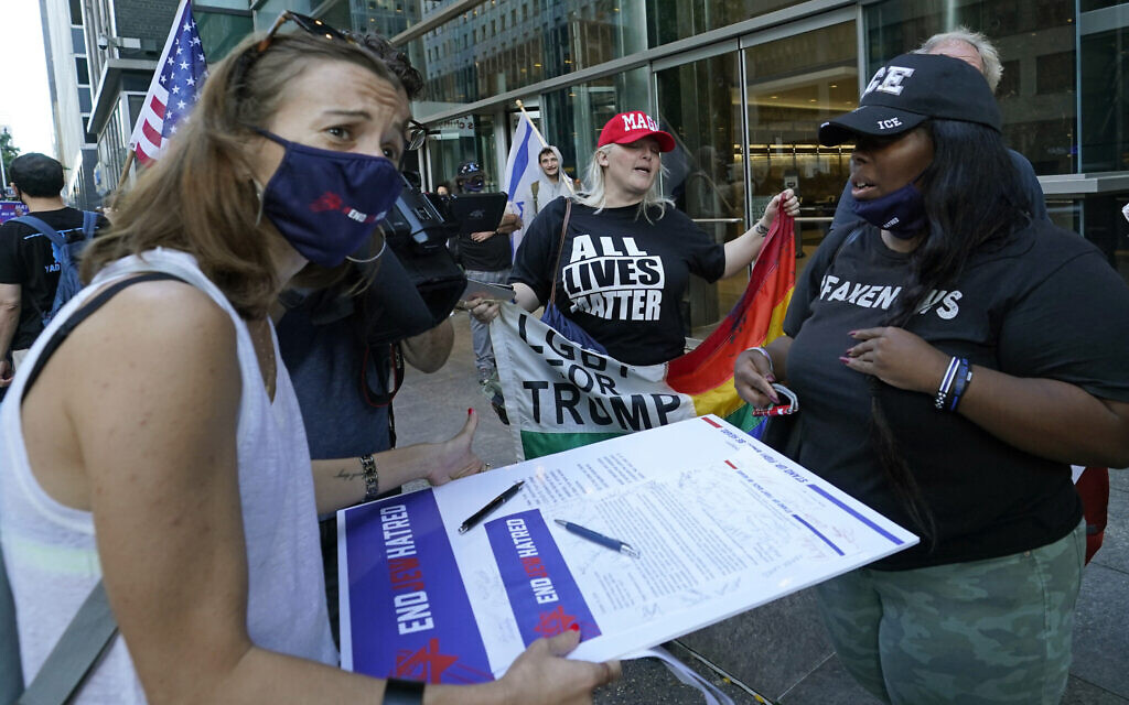 A woman encourages people to sign a petition calling for an end to "Jew Hatred," outside the offices of then-New York governor Andrew Cuomo, October 15, 2020. (AP Photo/Kathy Willens)