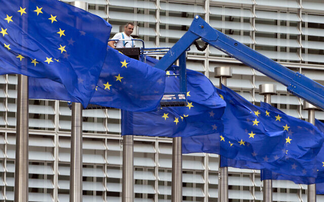 A worker on a lift adjusts the EU flags in front of EU headquarters in Brussels, June 23, 2016. (AP Photo/Virginia Mayo, File)