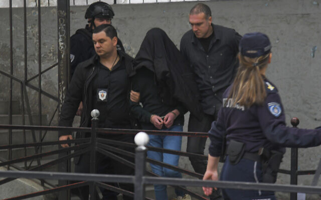 A suspect is escorted by police outside the Vladislav Ribnikar school in Belgrade, Serbia, May 3, 2023. (AP Photo)