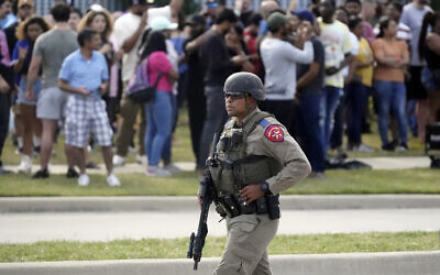 A law enforcement officer walks as people are evacuated from a shopping center where a shooting occurred Saturday, May 6, 2023, in Allen, Texas. (AP Photo/LM Otero)