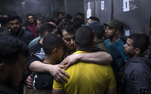 Mourners comfort each other in the morgue of Al-Shifa Hospital after Israeli airstrikes killed a dozen Palestinians in Gaza City, Tuesday, May 9, 2023. The Israeli military says it has killed three senior commanders of the Islamic Jihad group in targeted airstrikes. (AP Photo/Fatima Shbair)