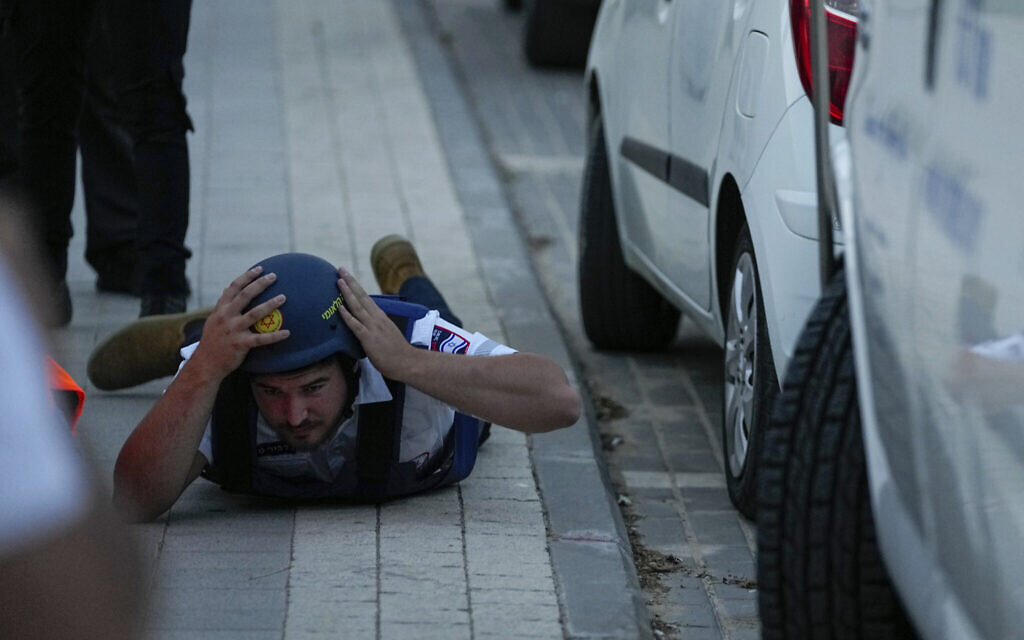 An Israeli paramedic takes cover as a siren sounds warning of incoming rockets fired from the Gaza Strip, in the southern Israeli town of Sderot, May 11, 2023. (AP Photo/Ohad Zwigenberg)