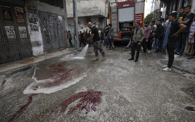 Palestinian firefighters clean blood stains at the site where two Palestinian gunmen where killed during an Israeli army raid in the Balata refugee camp in the West Bank city of Nablus, May 13, 2023. (AP Photo/Majdi Mohammed)