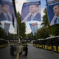 Commuters wait for buses next to election banners of Turkish President and People's Alliance's presidential candidate Recep Tayyip Erdogan, top, and Turkish CHP party leader and Nation Alliance's presidential candidate Kemal Kilicdaroglu, background, in Istanbul, Turkey, Tuesday, May 23, 2023. (AP/Francisco Seco)