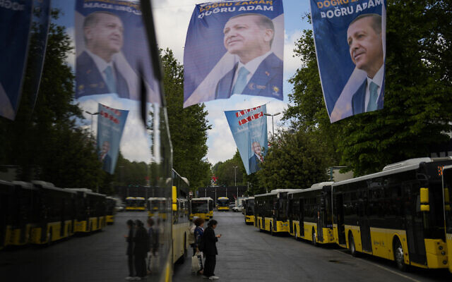 Commuters wait for buses next to election banners of Turkish President and People's Alliance's presidential candidate Recep Tayyip Erdogan, top, and Turkish CHP party leader and Nation Alliance's presidential candidate Kemal Kilicdaroglu, background, in Istanbul, Turkey, Tuesday, May 23, 2023. (AP/Francisco Seco)