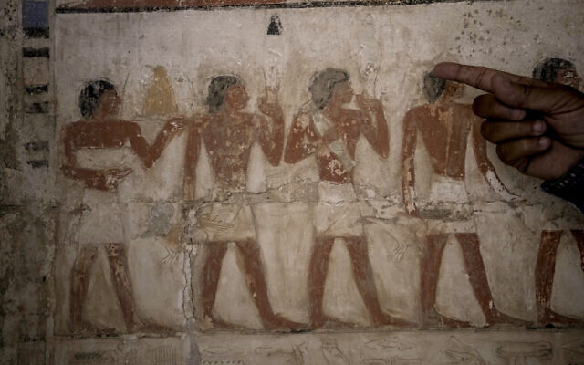 An Egyptian archeologist points at a colored painting showing a sacrifice offering at a recently uncovered tomb that was said to belong to a top official of the fifth Dynasty named 'Ne Hesut Ba' (2,400 BCE), at the site of the Step Pyramid of Djoser in Saqqara, Egypt, May 27, 2023. (AP Photo/Amr Nabil)