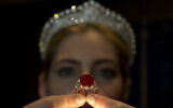 An employee of Sotheby's auction house holds up the 'Sunrise Ruby' ring, a cushion shaped Myanmar ruby of some 25.59 carats of pigeon blood colour during a photocall in London, April 8, 2015. (Alastair Grant/AP)