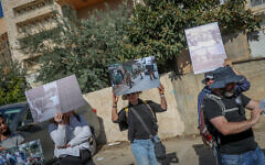 Members of the left-wing NGO Breaking the Silence hold images  allegedly showing abuses by the Israeli military, during a tour in the West Bank city of Hebron, November 2, 2022. (Flash90)