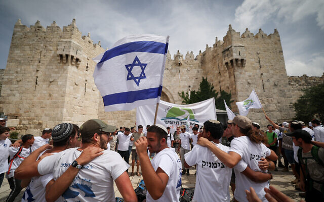 Young Jewish men hold Israeli flags as they dance at Damascus Gate in Jerusalem's Old City, during Jerusalem Day celebrations, May 18, 2023. (Yonatan Sindel/Flash90)