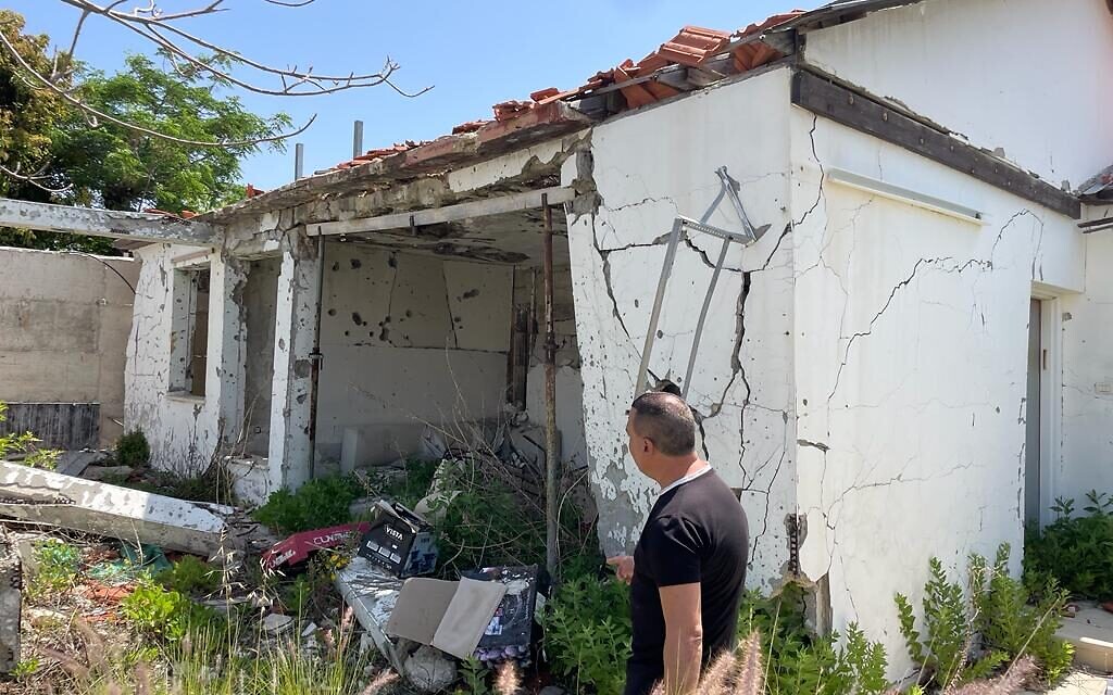 Neighbor Avishai Cohen stands in from of a destroyed home from a previous rocket attack in Ashkelon, May 11, 2023 (Carrie Keller-Lynn/The Times of Israel)