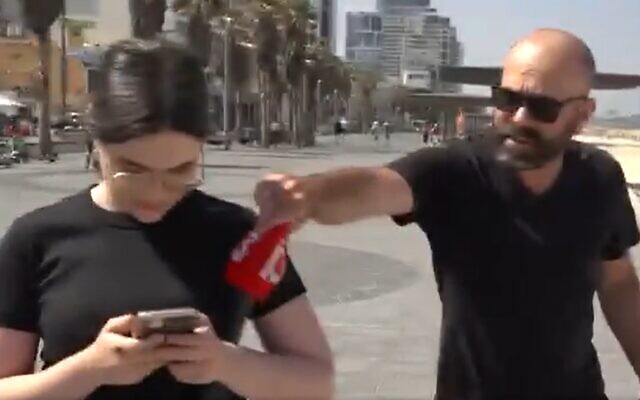 A man, right, snatches the covering off the microphone of Channel 13 reporter Talya Cohen before pepper spraying the team of journalists, in Tel Aviv, May 10, 2023. (Screenshot: Twitter; used in accordance with Clause 27a of the Copyright Law)