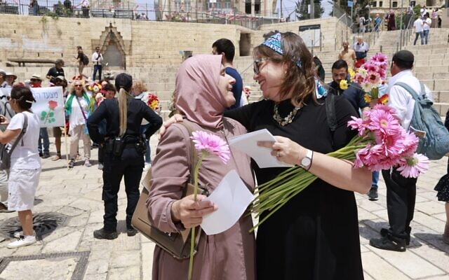 A Tag Meir coexistence activist gives a Muslim woman a flower during the organization's ninth annual Flower March through the Old City of Jerusalem designed to spread a message of "love, inclusion and solidarity" ahead of the nationalist Jerusalem Day Flag March, May 18, 2023. (Yossi Zamir/Tag Meir)