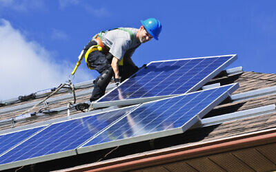 Installing solar panels on a roof. (Elenathewise, iStock at Getty Images)