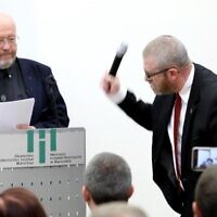 Polish-Canadian historian Jan Grabowski stands at the podium for a planned lecture as far-right lawmaker Grzegorz Braun of Poland’s Confederation party grabs the microphone and smashes it, at the German Historical Institute in Warsaw, Poland, May 30, 2023. (Courtesy of Jan Grabowski via JTA)