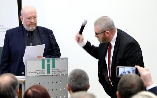 Polish-Canadian historian Jan Grabowski stands at the podium for a planned lecture as far-right lawmaker Grzegorz Braun of Poland’s Confederation party grabs the microphone and smashes it, at the German Historical Institute in Warsaw, Poland, May 30, 2023. (Courtesy of Jan Grabowski via JTA)