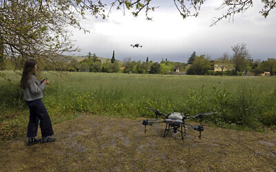 A picture taken on April 13, 2023, shows an employee of the agronomy tech company AgroScout flying a drone in the northern Israeli kibbutz of Yiron. (Menahem Kahana/AFP)