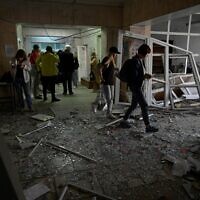 Visitors walk through debris in the hall of a health clinic damaged as a result of a downed missile explosion in Kyiv, on June 1, 2023. (Sergei CHUZAVKOV / AFP)