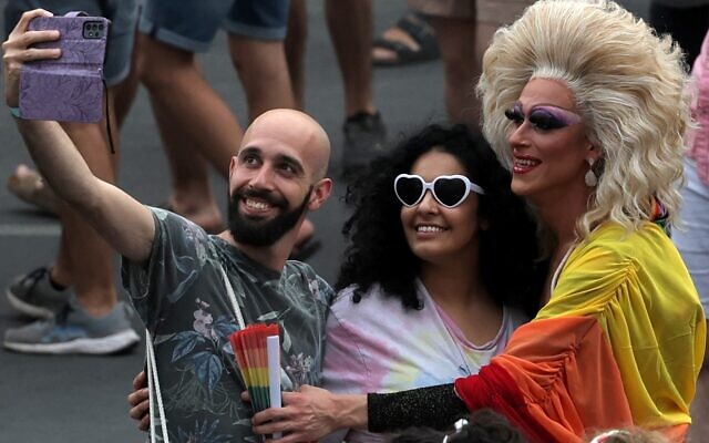 People pose for a selfie photo with a person dressed in drag during the 21st annual Jerusalem Pride Parade in Jerusalem on June 1, 2023. (AHMAD GHARABLI / AFP)