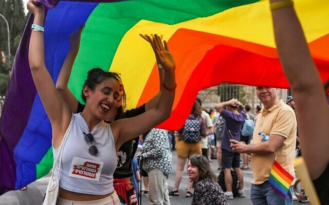 People dance underneath a giant rainbow banner during the 21st annual Jerusalem Pride Parade in Jerusalem on June 1, 2023. (AHMAD GHARABLI / AFP)