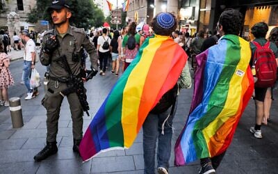 An Israeli Border Police guard stands guard as people draped in rainbow flags march during the 21st annual Jerusalem Pride Parade in Jerusalem on June 1, 2023. (Menahem KAHANA / AFP)