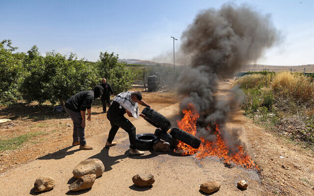 Members of the Druze community set tires aflame as they protest against an Israeli wind turbine project planned in agricultural lands near the village of Majdal Shams in the Golan Heights on June 21, 2023. (Photo by Jalaa MAREY / AFP)
