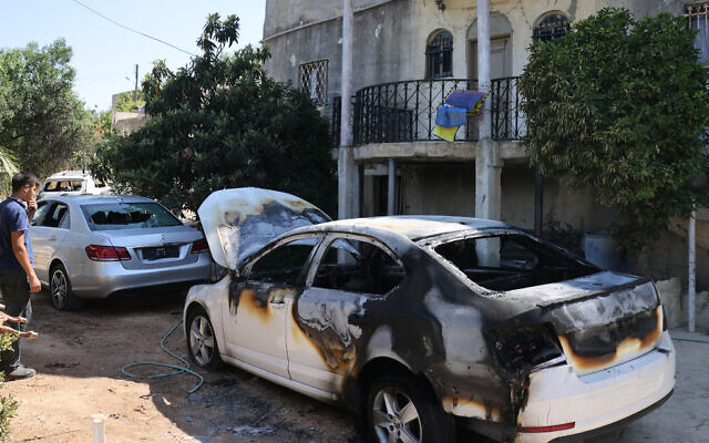 A man checks a burnt car, reportedly set ablaze by Israeli settlers, in the area of Luban a-Sharqiya in the West Bank on June 21, 2023. (AHMAD GHARABLI / AFP)