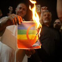 Supporters of Iraqi Shiite cleric Moqtada Sadr burn a poster depicting an LGBTQ+ flag during a protest in Karbala on June 29, 2023. (Mohammed Sawaf/AFP)