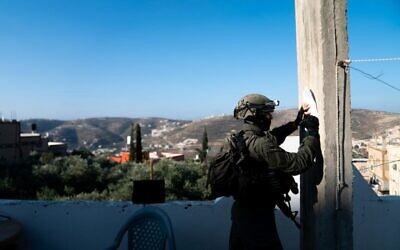 An Israeli soldier takes measurements at the home of a Hamas-affiliated terrorist, who carried out a deadly attack near the Eli settlement, in the West Bank town of Urif, June 22, 2023. (Israel Defense Forces)