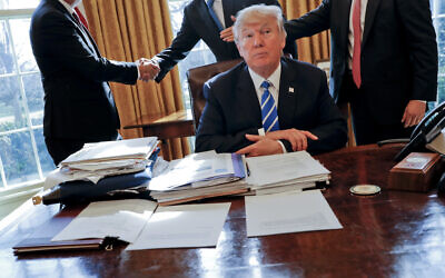 US President Donald Trump sits at his desk after a meeting with Intel CEO Brian Krzanich, left, and members of his staff in the Oval Office of the White House in Washington, Feb. 8, 2017, as a lockbag is visible on the desk, the key still inside at left. (AP Photo/Pablo Martinez Monsivais, File)