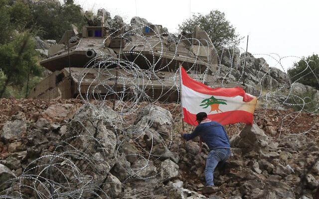 A Lebanese protester sets a Lebanese flag near an Israeli Merkava tank along the border on Friday, June 9, 2023. (AP Photo/Mohammad Zaatari)