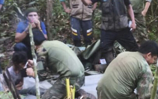 In this photo released by Colombia's Armed Forces Press Office, soldiers and Indigenous men tend to the four children who were missing after a deadly plane crash, in the Solano jungle, Caqueta state, Colombia, June 9, 2023. (Colombia's Armed Force Press Office via AP)