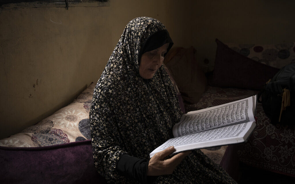 Huda Zaqqout reads from a large copy of a Muslim holy book at her home, a few weeks before she is slated to travel to Mecca for the Muslim pilgrimage of hajj, in Gaza City, May 31, 2023. (AP Photo/Fatima Shbair)