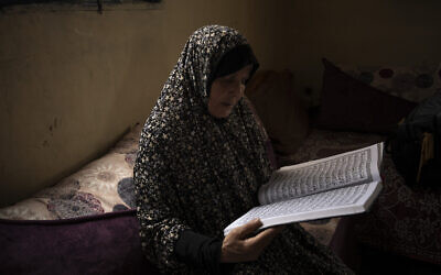 Huda Zaqqout reads from a large copy of a Muslim holy book at her home, a few weeks before she is slated to travel to Mecca for the Muslim pilgrimage of hajj, in Gaza City, May 31, 2023. (AP Photo/Fatima Shbair)