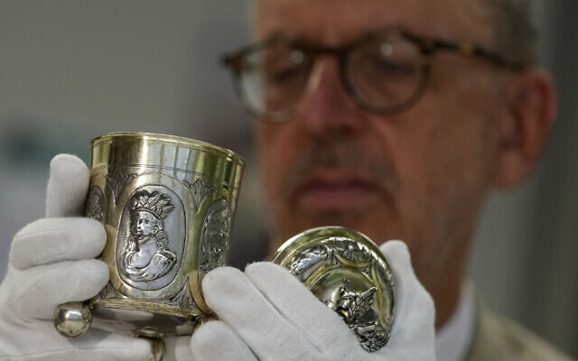 Matthias Weniger, curator of the Bavarian National Museum, lifts one of 111 silver objects, stolen by the Nazis from Jews during the Third Reich, in Munich, Germany, June 10, 2023. (AP Photo/Matthias Schrader)