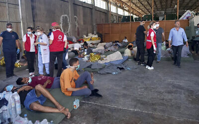 Survivors of a migrant shipwreck sit at a warehouse at the port in Kalamata town, about 240 kilometers (150 miles) southwest of Athens, Greece, June 14, 2023. (www.argolikeseidhseis.gr via AP)